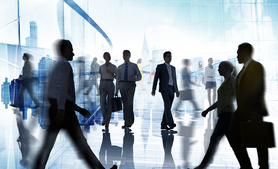 Business professionals walking in a modern office setting with a blurred cityscape background.