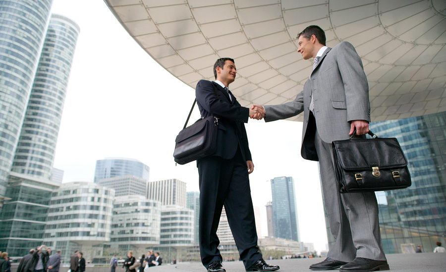 Two business professionals shaking hands in an urban outdoor setting