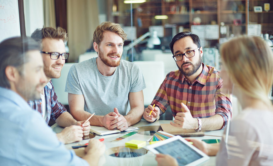 Group of colleagues in a brainstorming session around a table in a modern office setting.