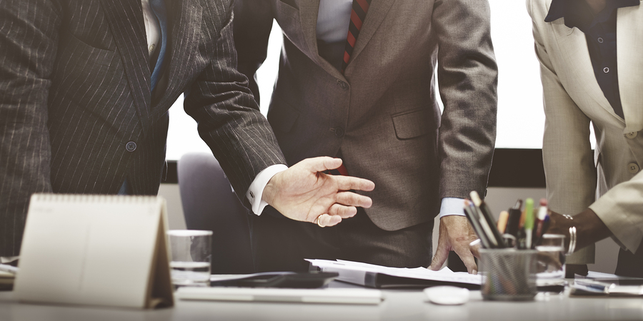 Business professionals discussing documents at a desk.