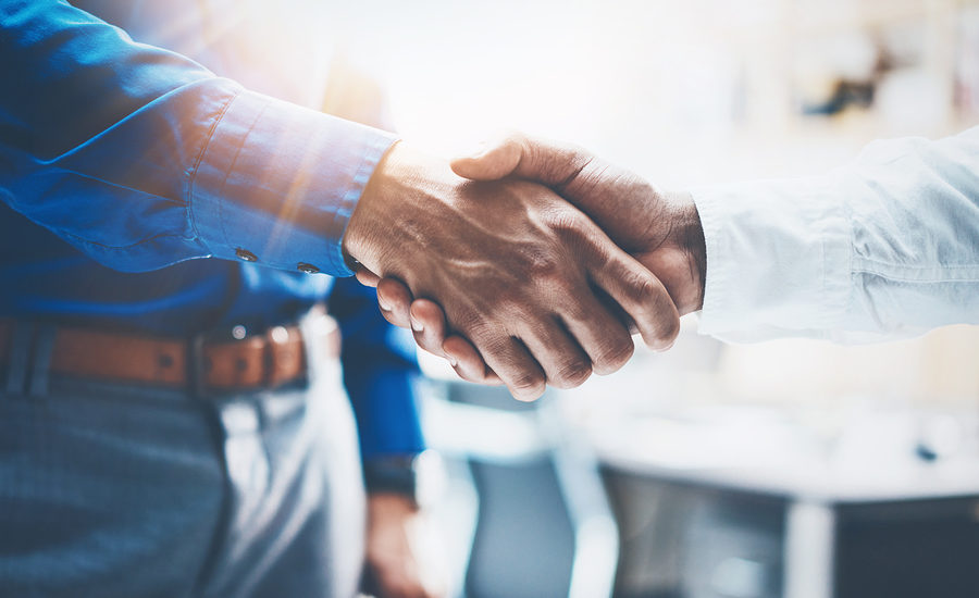Close-up of a handshake between two professionals in a bright office setting.