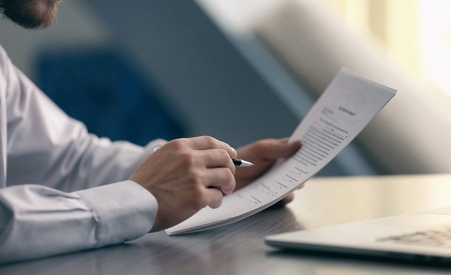 Business professional reviewing a document at a desk.