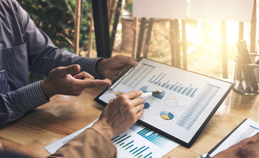 Business professionals analyzing financial charts and graphs on a tablet.