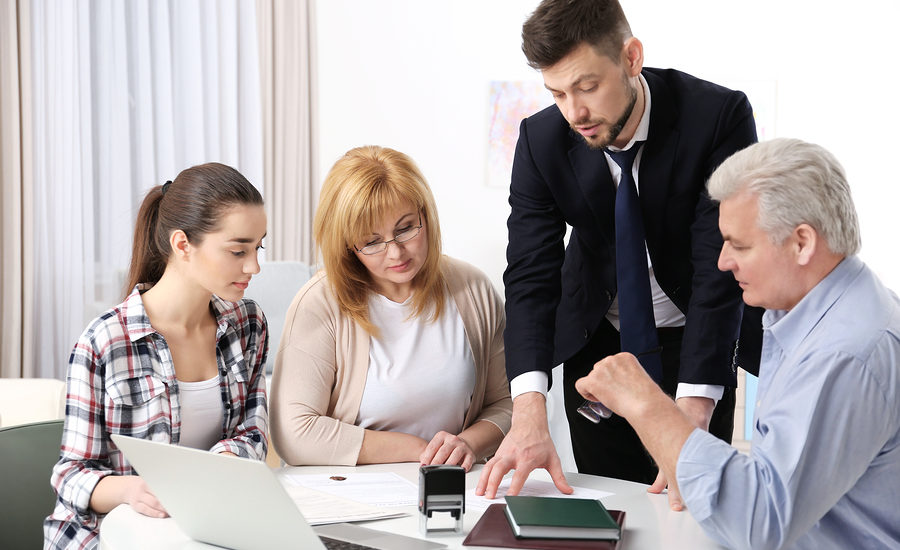 Business professional explaining documents to a group during a meeting.