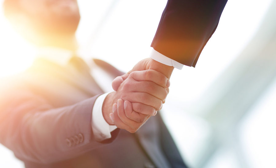 Close-up of a handshake between two professionals in a sunlit office.