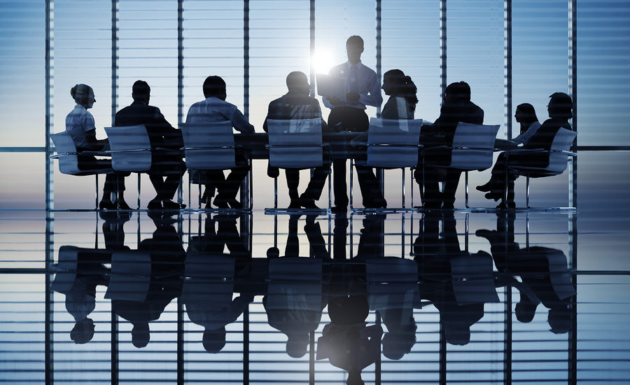Silhouettes of business professionals in a boardroom during a meeting.