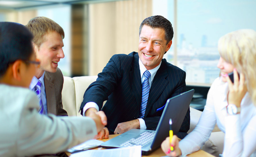 Business professional smiling while shaking hands during a meeting.