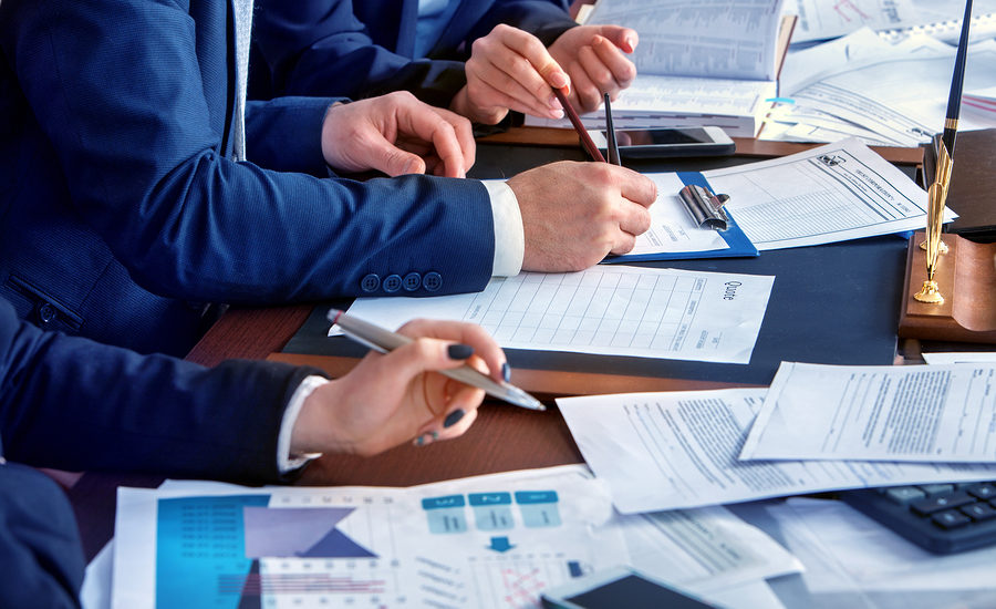 Business professionals collaborating on documents and financial data at a table.