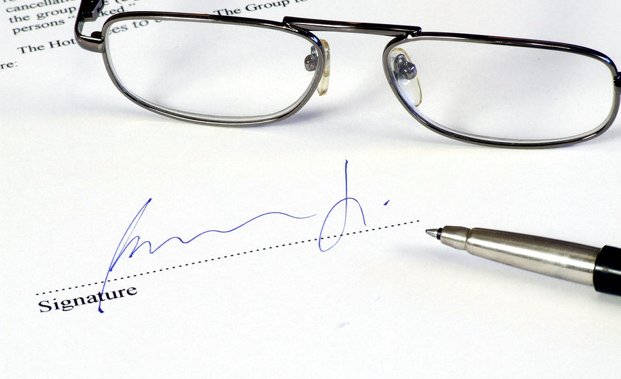 Signed document with glasses and a pen on a table.