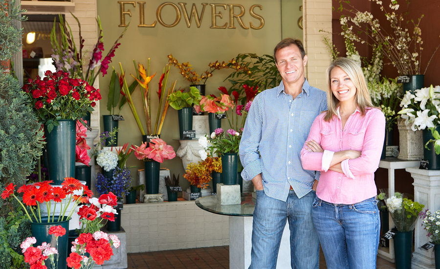 smiling business owners standing outside a flower shop