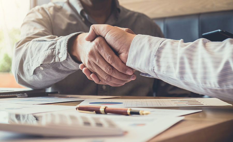 Handshake over paperwork and pen on a desk