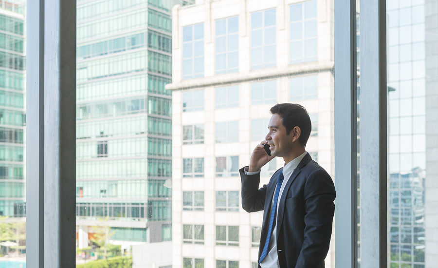 Business professional making a phone call in a modern office with a cityscape view.