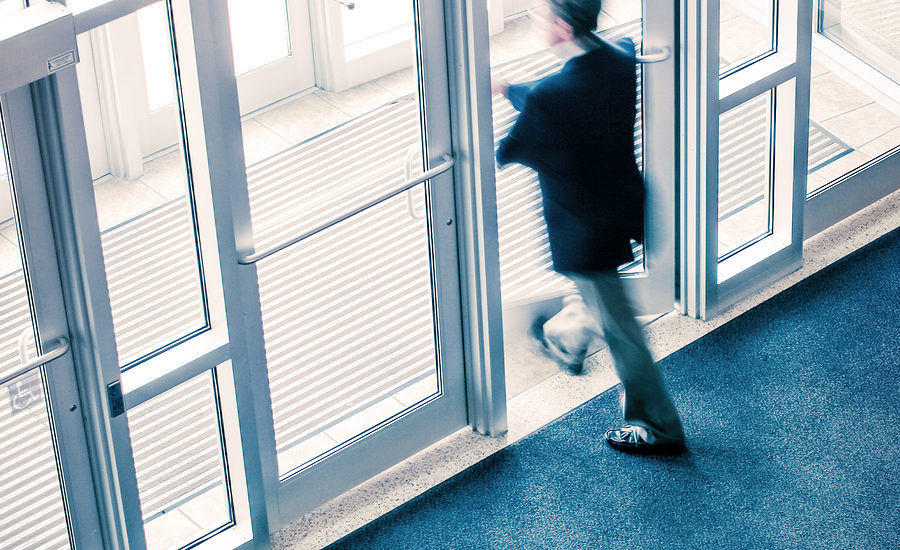 A blurred person exiting through glass double doors.