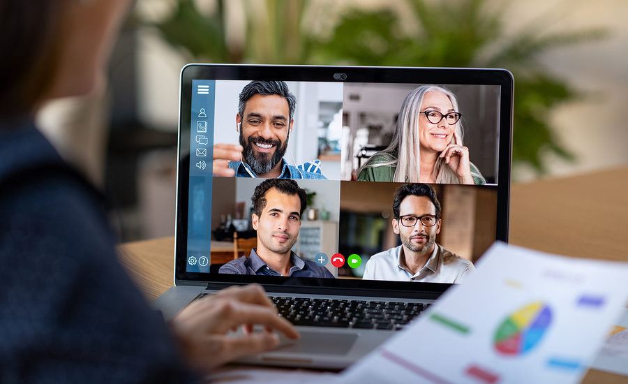 Person holding a virtual business meeting on a laptop screen with multiple colleagues.