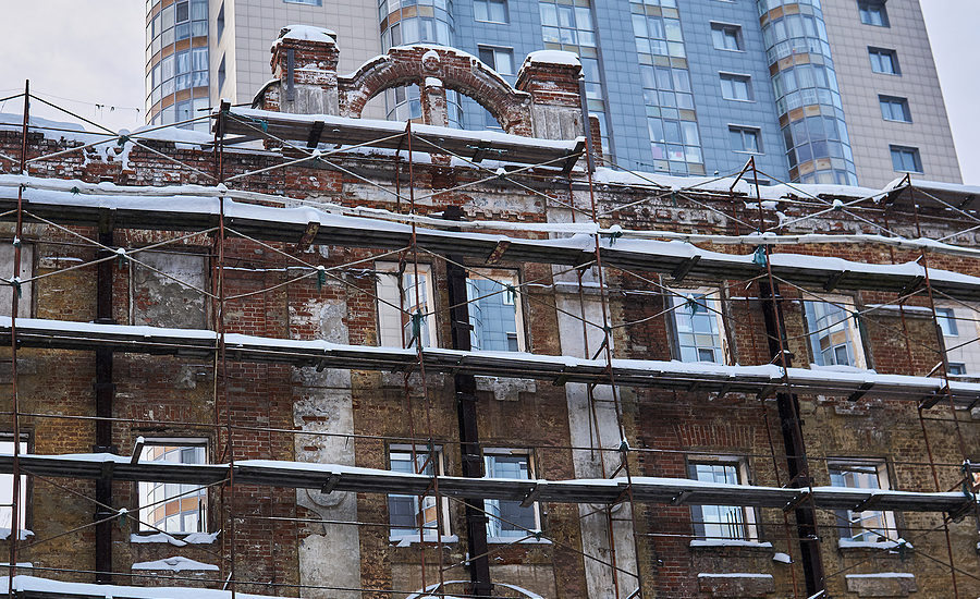 facade of an old brick building under renovation with scaffolding and snow-covered surfaces