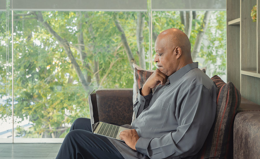 Mature businessman working on a laptop while seated in a modern lounge with a scenic view.
