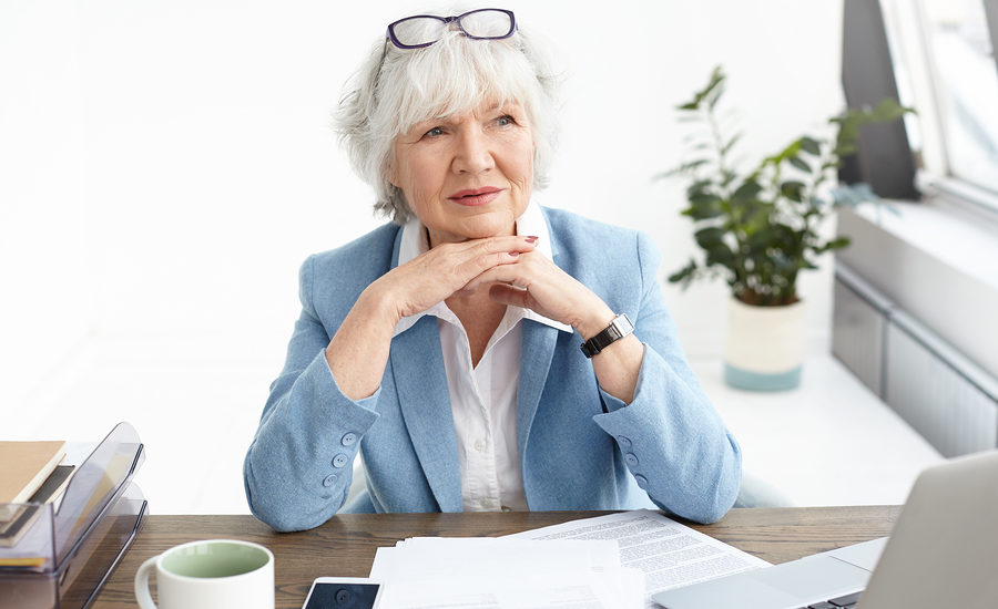 An experienced professional woman sitting at her desk, thoughtfully looking ahead.