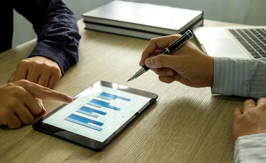 Business discussion with tablet displaying bar graph.
