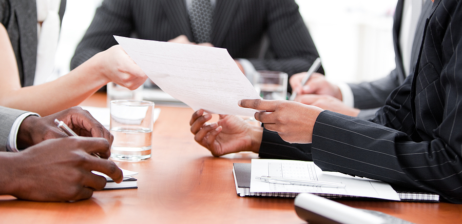 Close-up of multi-ethnic business team reviewing documents at a meeting table
