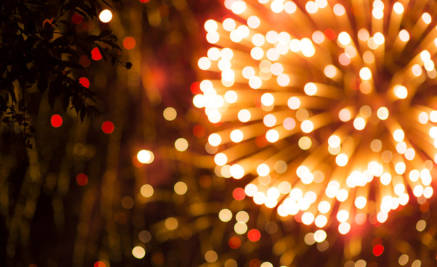 Vibrant fireworks display with bokeh lights in the foreground.