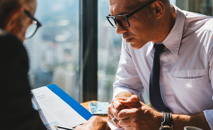Business professional attentively reviewing a document during a meeting in a modern office.