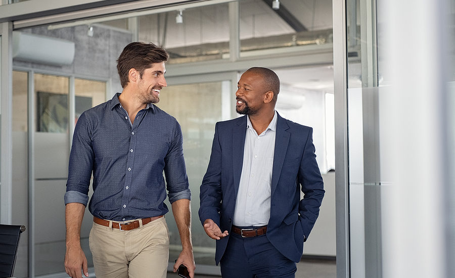 Two business professionals walking and talking in a modern office environment.