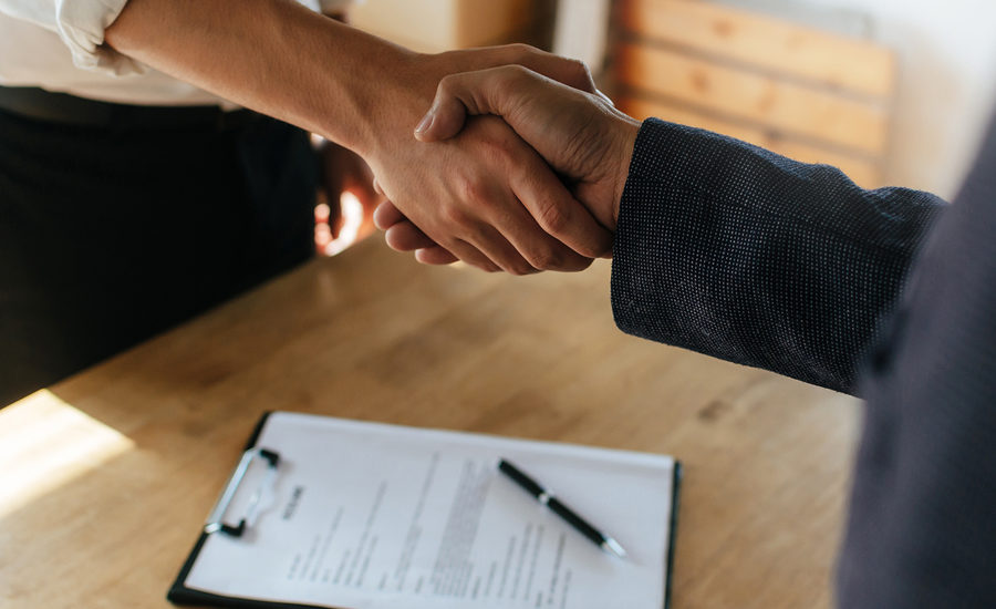 Close-up handshake over a contract on a clipboard