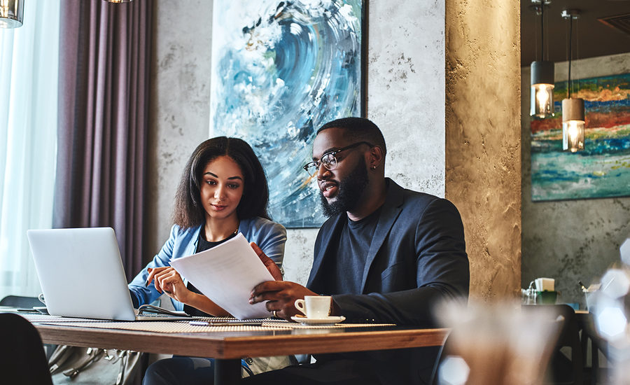 Two business professionals reviewing documents and discussing strategy in a modern, stylish setting.