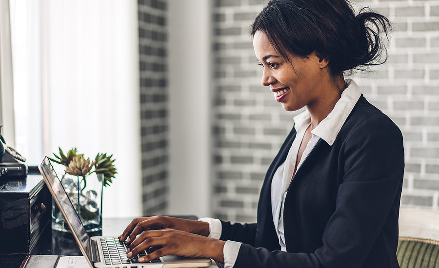 Smiling businesswoman working on a laptop in an office setting.