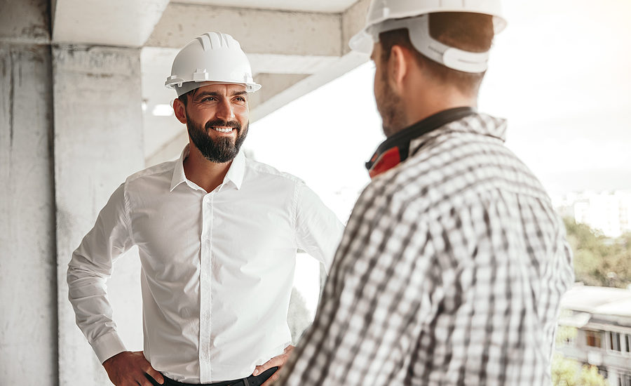 Construction professionals wearing hard hats discussing a project on-site.