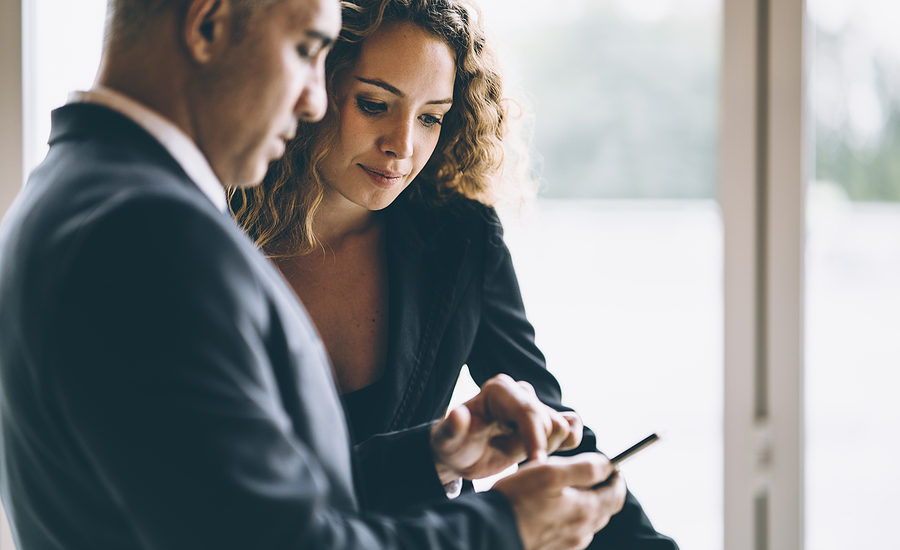 Two business professionals discussing information on a smartphone.