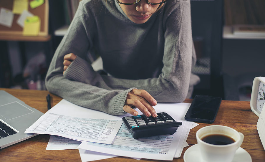 Woman calculating finances at a desk with a calculator and documents.
