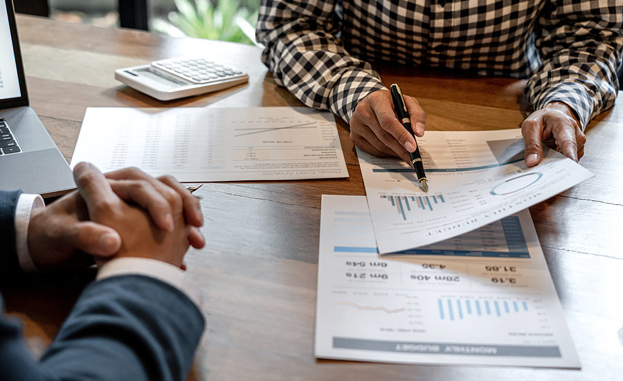 Close-up of business professionals reviewing financial reports and charts during a meeting.