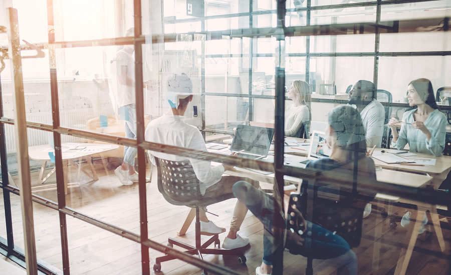 A group of professionals collaborating in a modern office space with glass walls.