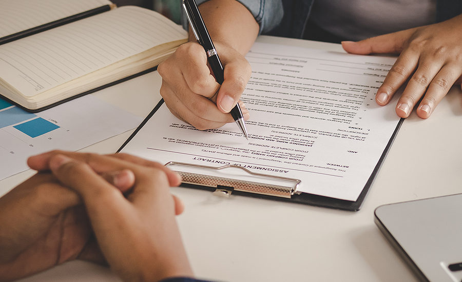 Close-up of a person signing a contract on a clipboard