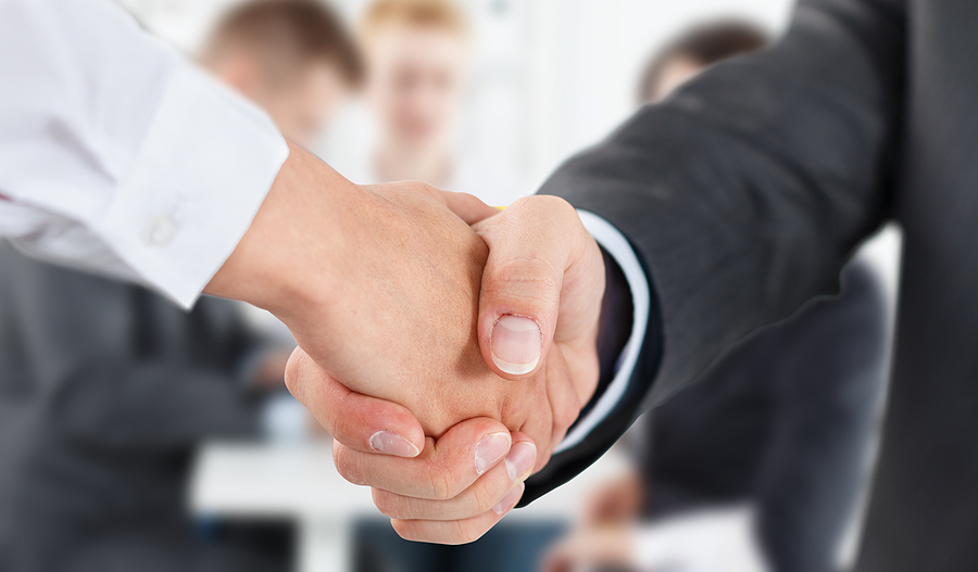 Close-up of a handshake between two professionals in an office setting.