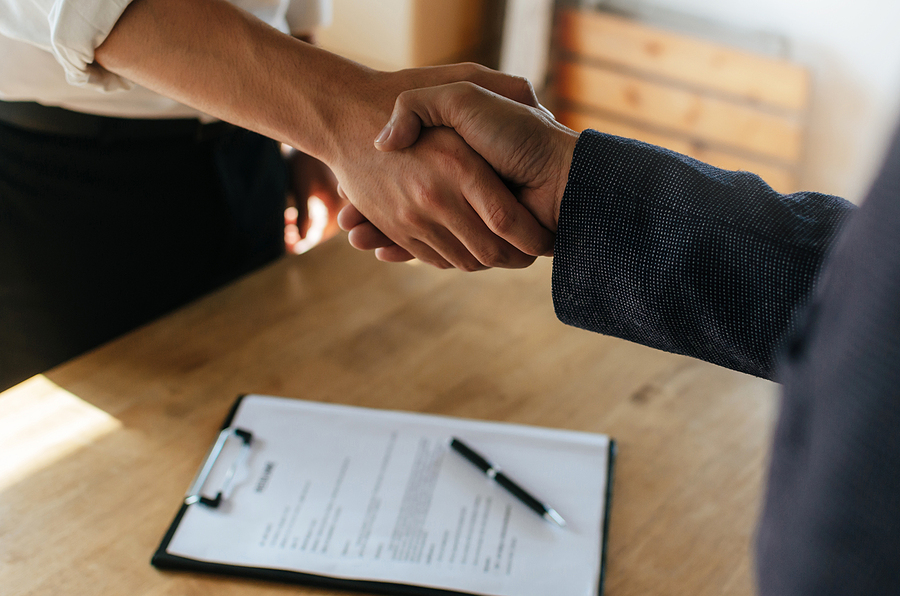 Close-up handshake over a contract on a clipboard